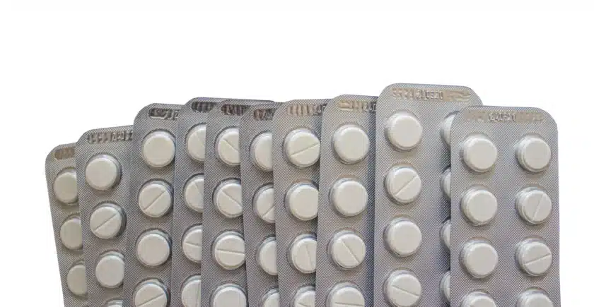 Close-up of multiple blister packs containing white round pills, arranged in a fan shape on a white background