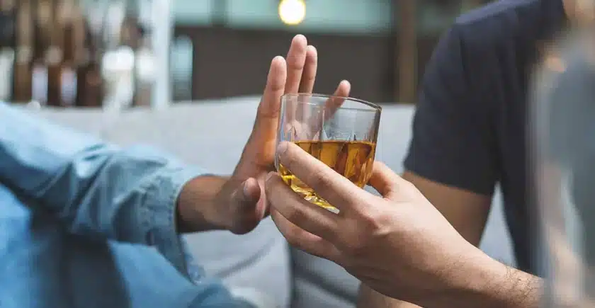 Hand pushing a glass of alcohol away.